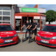 Die bei Reifen Popp zusätzlich zu klassischen Werkstattersatzwagen zum Einsatz kommenden rot-schwarzen E-Scooter im Toyo-Design sollen – sagen Jörg (links) und Felix Popp – zukünftig über hauseigenen Solarstrom geladen werden können (Bild: Reifen Popp)